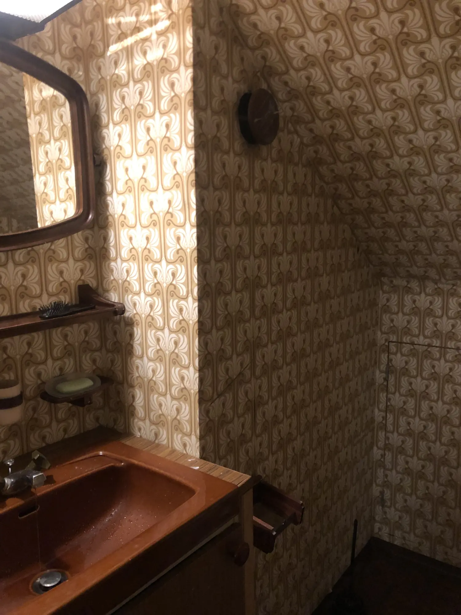 Badrum med tapet och gammal inredning före renovering