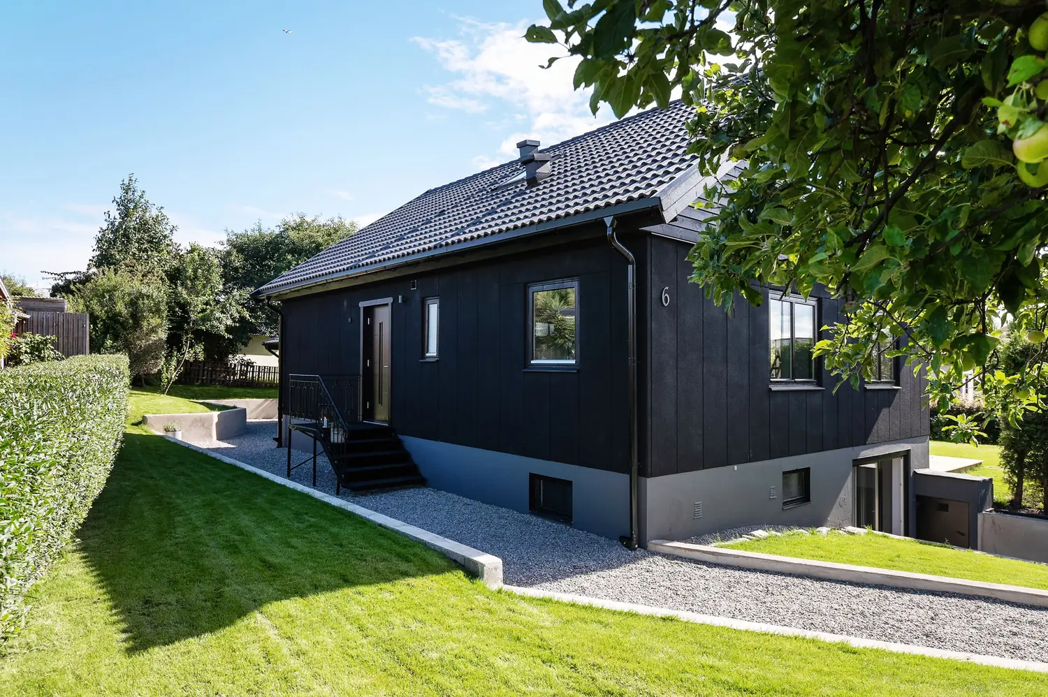 Mörkt hus med nylagd gräsmatta